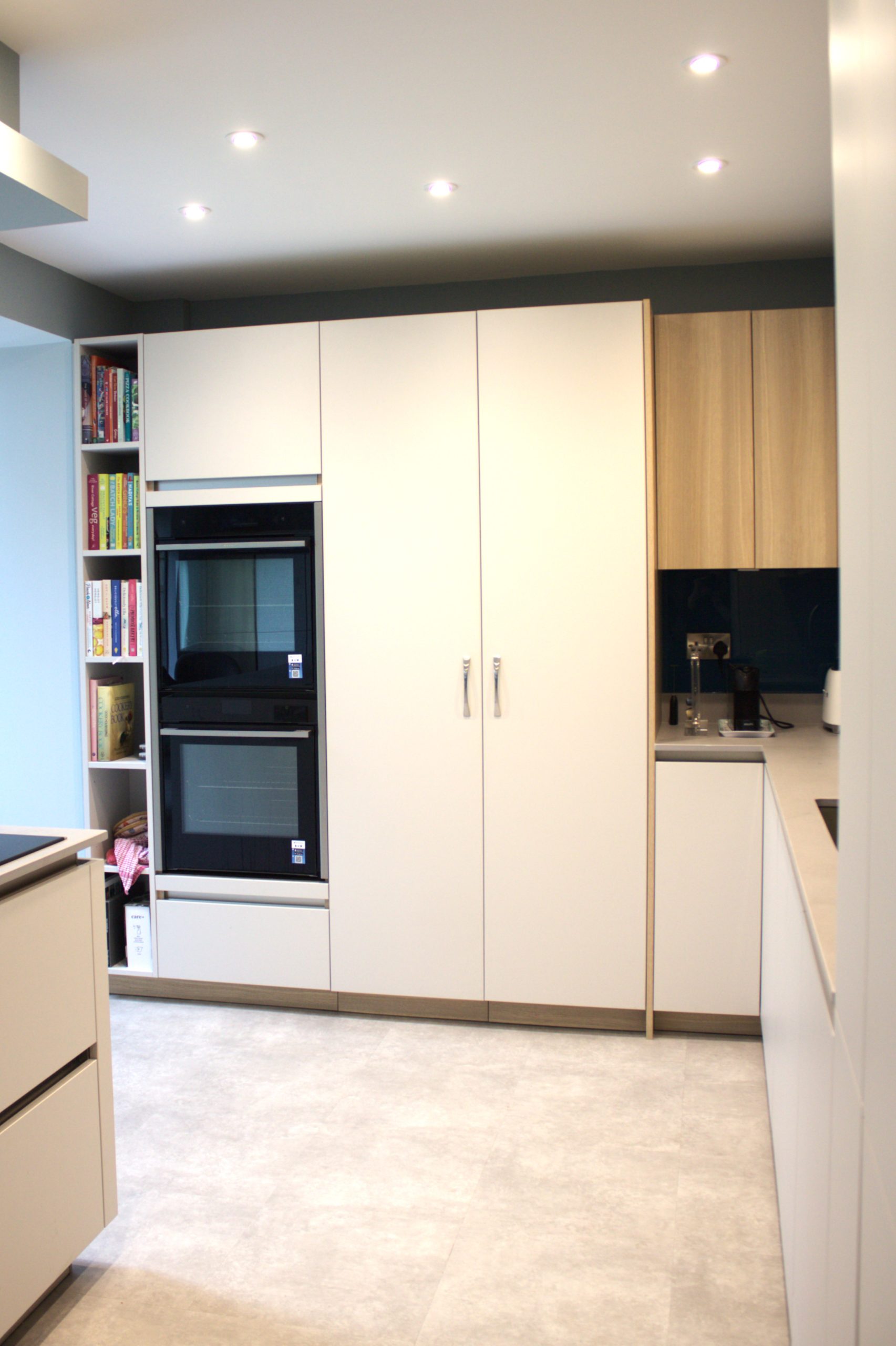 Tall white, built in cabinets are next to two ovens