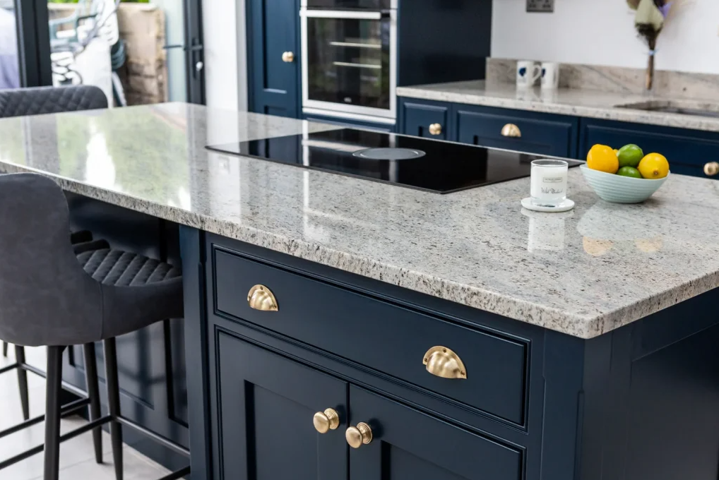 a light grey granite worktop with deep navy cabinets